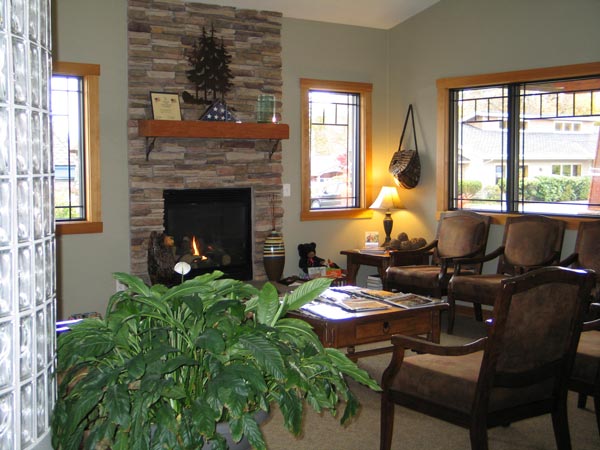 Side view of lobby area with chairs, fireplace, plant, and windows at The Center for Esthetic Dentistry in Grants Pass, OR 