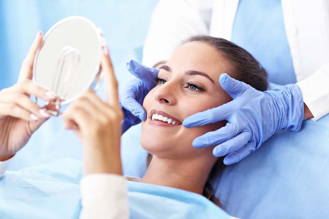 Image of a woman looking at her dental crowns that were placed, at The Center for Esthetic Dentistry in Grants Pass, OR.