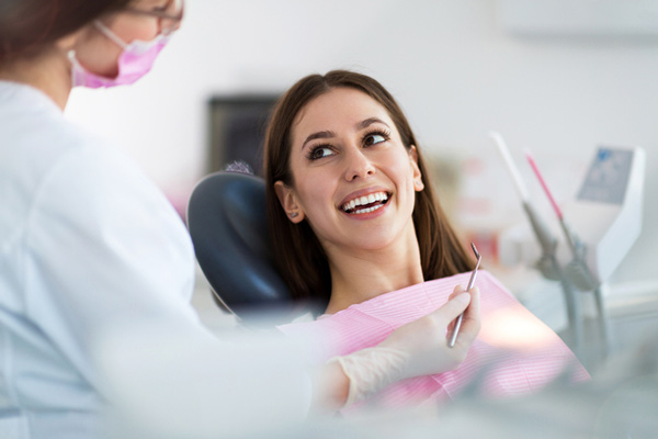 Woman leaning back in dental chair looking up at dentist