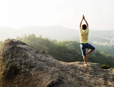 Image of person posing on top of mountain overlooking valley and trees near The Center for Esthetic Dentistry.